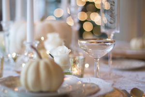 A decorated table with a cocktail glass and a white pumpkin