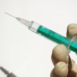 A close-up image of a hand holding a syringe with some liquid inside.