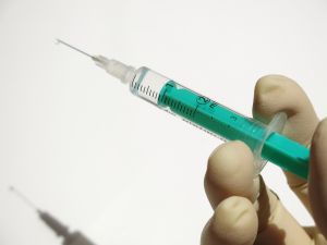A close-up image of a hand holding a syringe with some liquid inside.