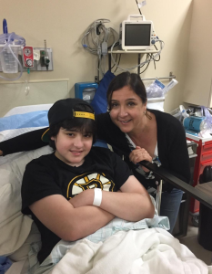 A woman with brown hair is hugging her son, who is in a hospital bed.